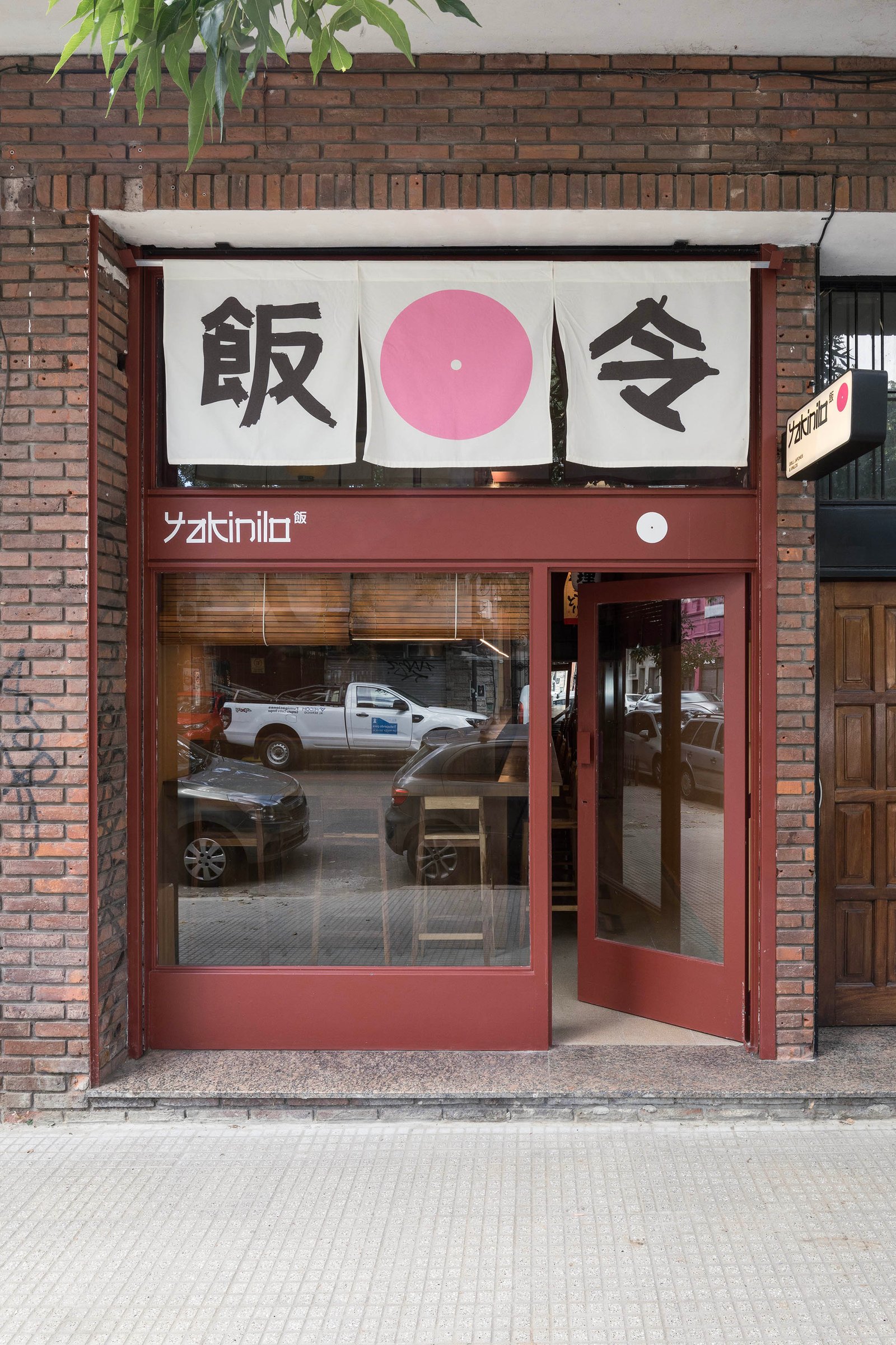 Fachada de local comercial con cartel japonés y entrada de vidrio — proyecto Yakinilo, por Estudio YME, en Av. Dorrego 1551